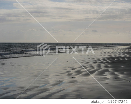 Seashore in sunlight with reflections on wet sand Seashore in sunlight with reflections on wet sand 119747242