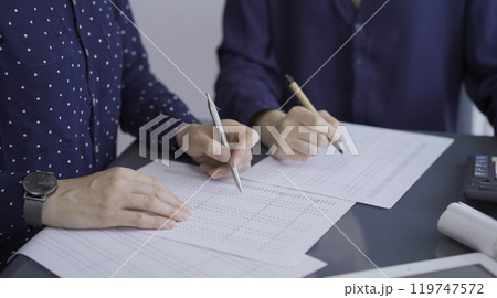 Female accountants or auditors reviewing financial data in office. Professionals analyzing paper reports and using calculator, close up. Audit and taxes Female accountants or auditors reviewing financial data in office. Professionals analyzing paper reports and using calculator, close up. Audit and taxes 119747572
