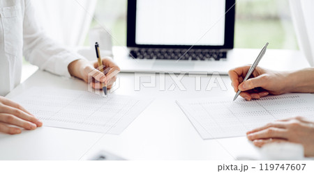 Two accountants using a laptop computer for counting taxes at white desk in office. Teamwork in business audit and finance 119747607