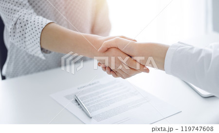Business people shaking hands above contract papers just signed on the white table, closeup. Lawyers at meeting. Teamwork, partnership, success concept 119747608