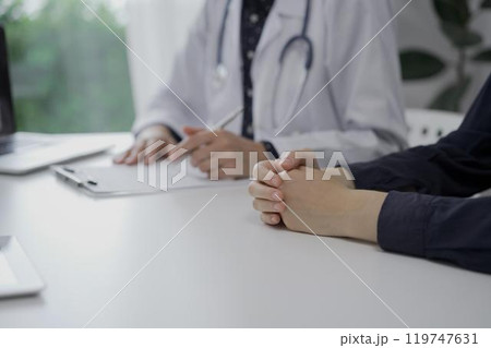 Doctor and a patient in clinic. The female physician is filling up medication history record form, close up of woman hands. Medicine concept Doctor and a patient in clinic. The female physician is filling up medication history record form, close up of woman hands. Medicine concept 119747631
