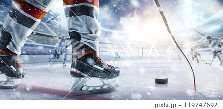 Hockey skates, stick and puck close-up. Hockey player in ice arena. Focus on the puck. Hockey concept. Ice. Hockey stadium 119747692