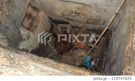 Old concrete cellar filled with accumulated garbage and debris in a neglected underground space 119747829