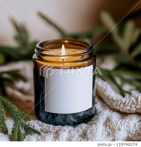 Amber glass candle jar with blank white label mockup, burning candle in Christmas holiday decorated home interior, seasonal cozy decor 119748274