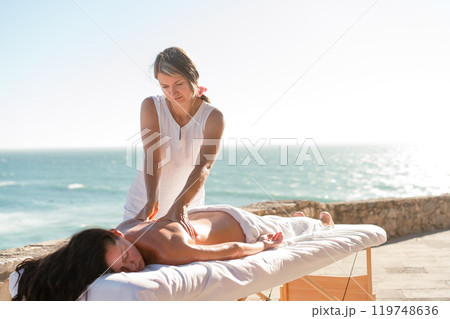 Therapist massaging woman's back on table at 119748636