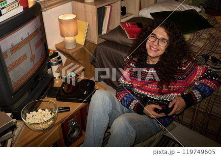 Smiling Person Playing Retro Video Game in Cozy Room 119749605
