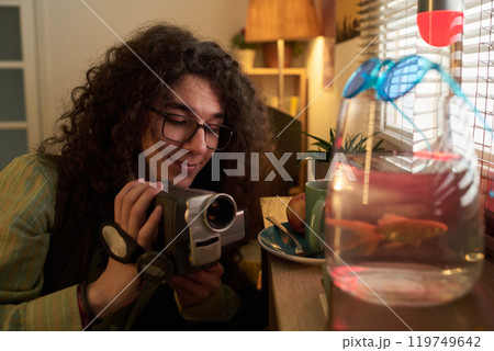 Smiling Woman Filming Goldfish Using Handheld Camera 119749642