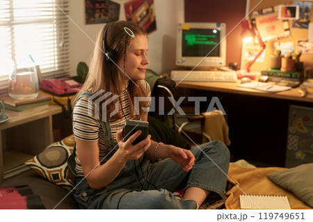 Enjoying Music in Cozy Bedroom Setting 119749651