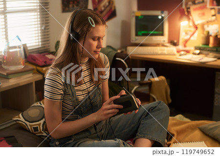Teenager Listening to Music in Retro-Themed Room 119749652