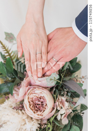 結婚指輪・マリッジリングをする新郎新婦の手とブーケ 119749856