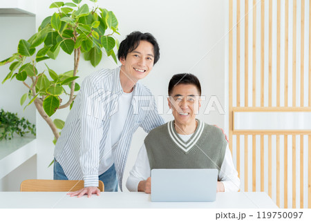 リビングでパソコンを操作するシニア男性 119750097