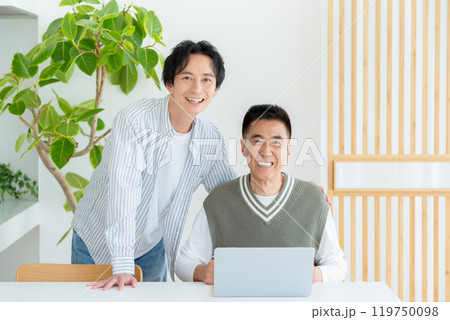 リビングでパソコンを操作するシニア男性 119750098