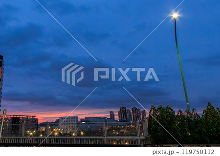 陸橋上から見る夕陽 武蔵小杉の高層マンション群の向こうに日が沈んでいる  川崎市JR新川崎駅2024 119750112
