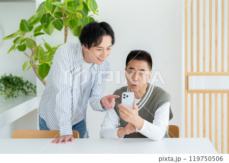 リビングでスマホを教わるシニア男性 119750506