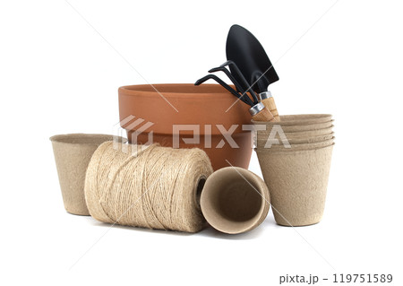 Gardening tools with terracotta pot, biodegradable pots, and spool of twine on a white background 119751589