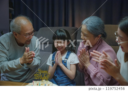 Happy Asian family grandparents and mother celebrating enjoy singing birthday song party with cake of granddaughter blowing candle at home in night time, Birthday surprise concept Happy Asian family grandparents and mother celebrating enjoy singing birthday song party with cake of granddaughter blowing candle at home in night time, Birthday surprise concept 119752456