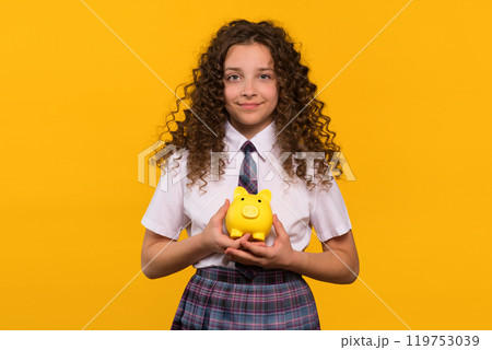 Girl in school uniform holding yellow piggy bank 119753039