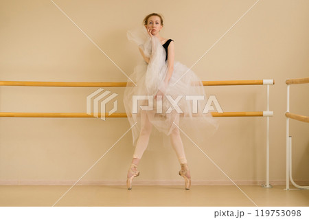 Ballet dancer performs striking pose in studio 119753098