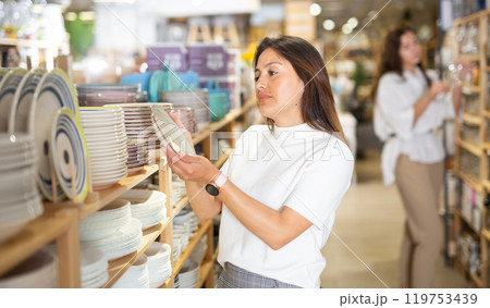 Latino american woman buying ceramic tableware in dishes shop Latino american woman buying ceramic tableware in dishes shop 119753439