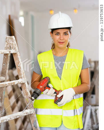 Female foreman in protective yellow vest and hard hat with screwdriver in hand Female foreman in protective yellow vest and hard hat with screwdriver in hand 119753653