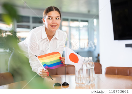Female office coordinator setting flags of Japan and LGBT community on negotiating table 119753661