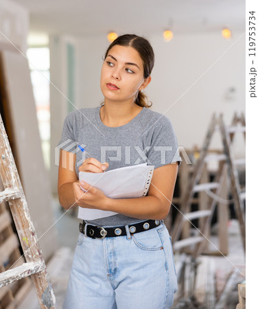 Female architect matching check list during repair works 119753734
