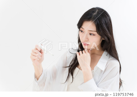 体温計を見ている若い女性 119753746