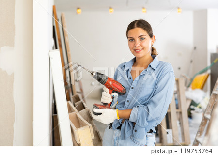 Portrait of smiling young woman with drill 119753764