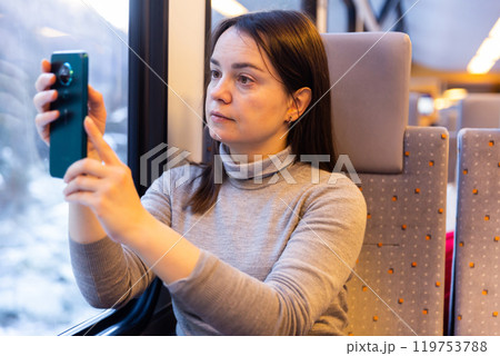 Woman enjoying journey in train, taking pictures on cellphone Woman enjoying journey in train, taking pictures on cellphone 119753788