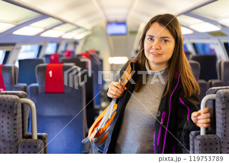 Smiling female backpacker standing in aisle between train seats Smiling female backpacker standing in aisle between train seats 119753789