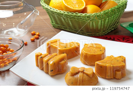 Frozen sea buckthorn and orange tea in Christmas molds on white plate in kitchen. Healthy eating and seasons.  119754747