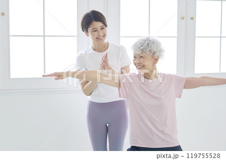 高齢者の女性にヨガを教えるインストラクター 119755528