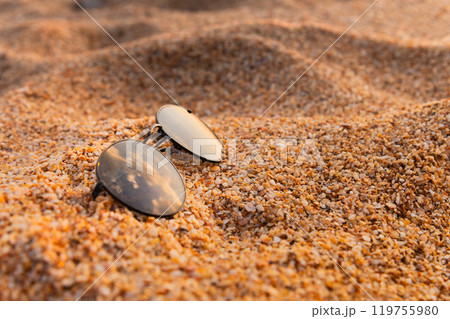 sunglasses lying on the beach on wet sandy sand. close up of stylish accessory during vacation, nobody sunglasses lying on the beach on wet sandy sand. close up of stylish accessory during vacation, nobody 119755980