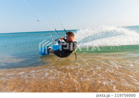 close up of cheerful young man riding fast on kiteboard creating wave and splashes in the sea close up of cheerful young man riding fast on kiteboard creating wave and splashes in the sea 119756000