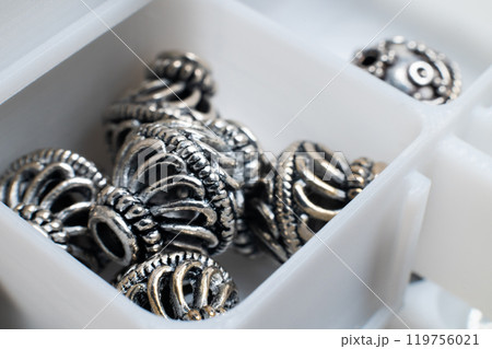 Metal jewelry elements, bracelet links lie in a storage box in a jewelry workshop 119756021
