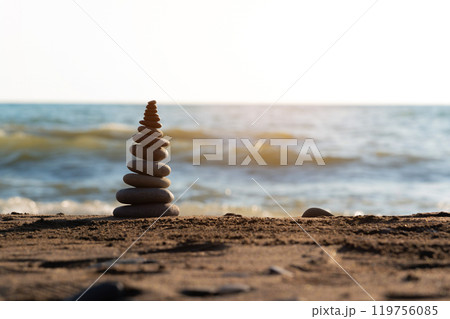Pyramid stones balance on the sand of the beach. The object is in focus, the background is blurred. Tranquility on the seashore, meditative process in building a pyramid of stones Pyramid stones balance on the sand of the beach. The object is in focus, the background is blurred. Tranquility on the seashore, meditative process in building a pyramid of stones 119756085