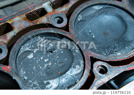 An exposed disassembled internal combustion engine. The engine block contains dirty pistons with carbon deposits and broken pieces of metal. The concept of lack of car care and untimely engine service An exposed disassembled internal combustion engine. The engine block contains dirty pistons with carbon deposits and broken pieces of metal. The concept of lack of car care and untimely engine service 119756110