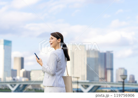 都市を背景にスマホを持つ女性 都市を背景にスマホを持つ女性 119756906