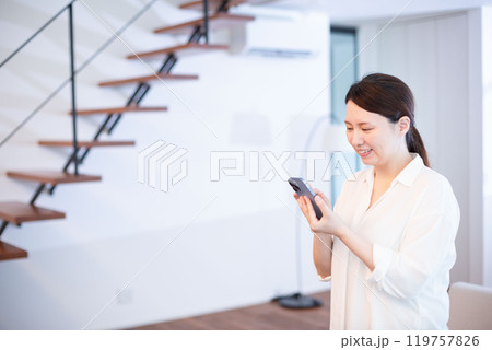 リビングでスマホを見る日本人女性 リビングでスマホを見る日本人女性 119757826