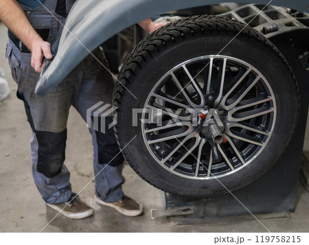Mechanic balancing a wheel in a workshop.  119758215