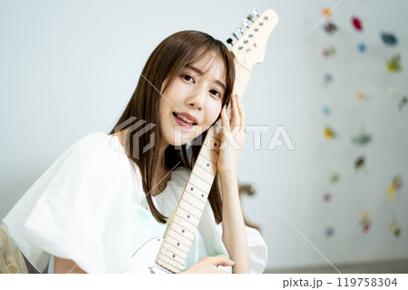 エレキギターを持つロングヘアの若い女性 119758304