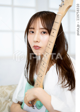 エレキギターを持つロングヘアの若い女性 エレキギターを持つロングヘアの若い女性 119758310