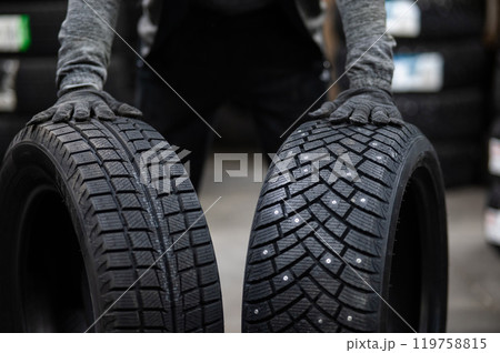 Mechanic keeps new summer and winter car tires in the garage. Comparison of wheels for different seasons.  119758815