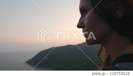 A woman stands by the shoreline, her gaze fixed on the endless expanse of the ocean spread out before her. A woman stands by the shoreline, her gaze fixed on the endless expanse of the ocean spread out before her. 119759528