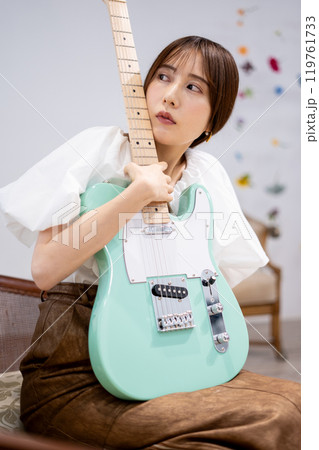 エレキギターを持つロングヘアの若い女性 119761733