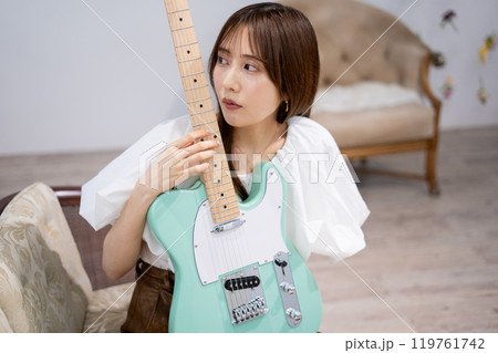 エレキギターを持つロングヘアの若い女性 エレキギターを持つロングヘアの若い女性 119761742