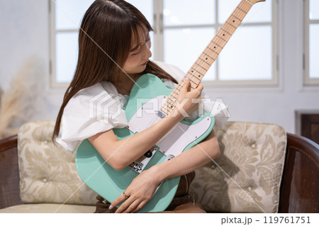 エレキギターを持つロングヘアの若い女性 119761751