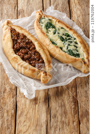 Turkish Pide Flat Bread Filled with ground beef, Cheese, Spinach and Herbs close-up on wooden board. Vertical 119762004