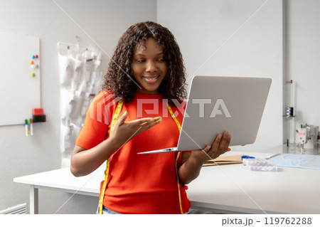 African american young seamstress with a laptop discussing something on the phone 119762288