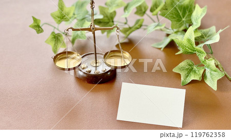 天秤と右側の白いカード_茶色背景 119762358